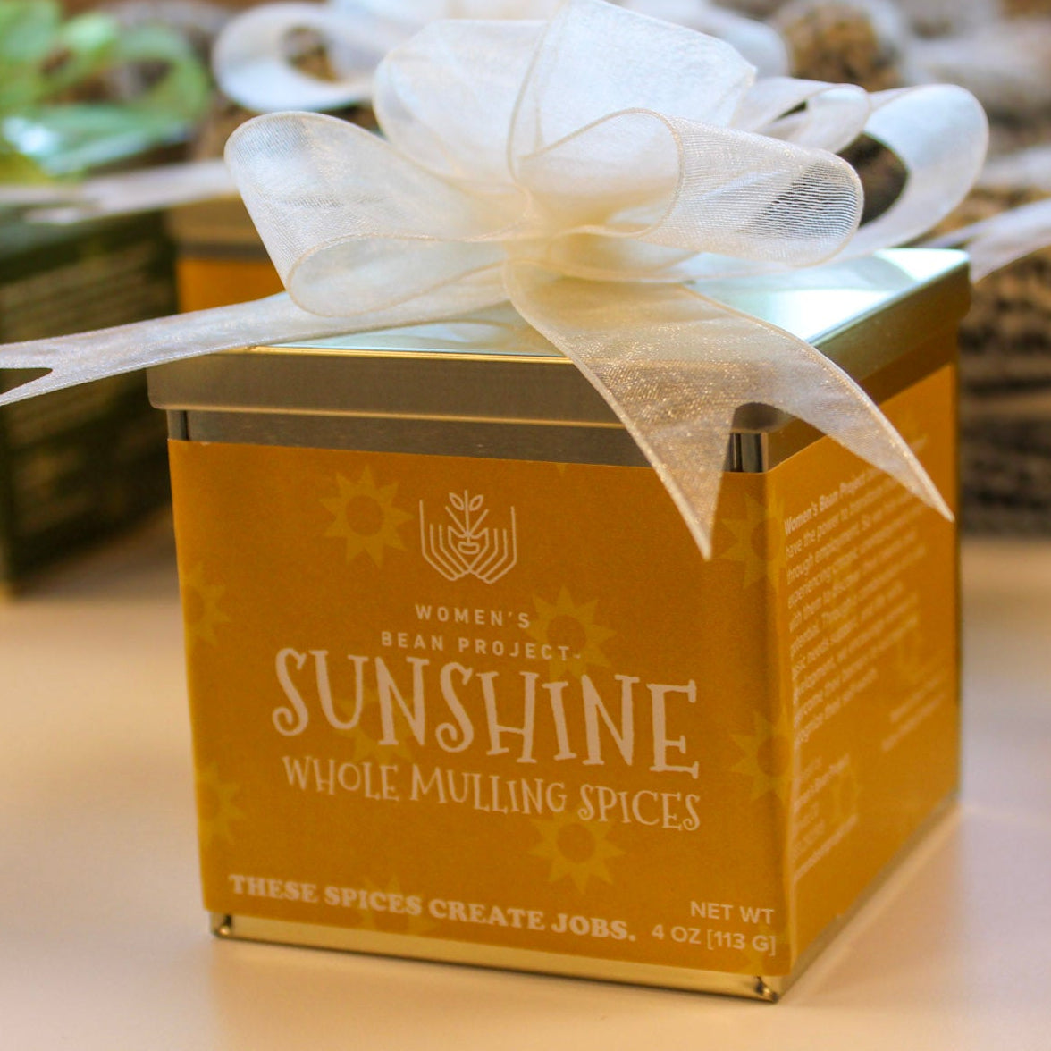 A box of Sunshine whole mulling spices with a white bow on a table.